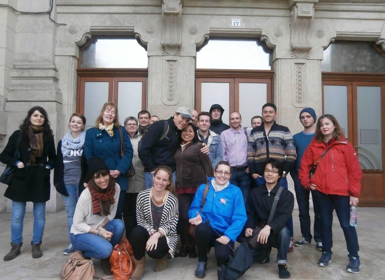 A group of people posing in front of a building with two large wooden doors and a stone facade. 2