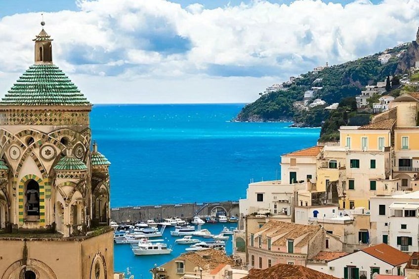 A coastal town with a prominent church, boats docked in the harbor, and buildings along the waterfront. 2