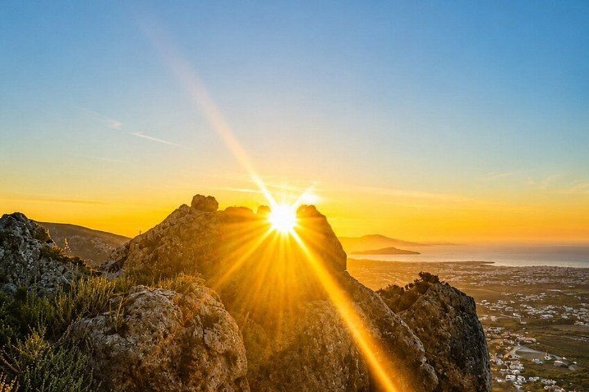 A sunset over rocky terrain with the sun shining through the gaps between the rocks. 4