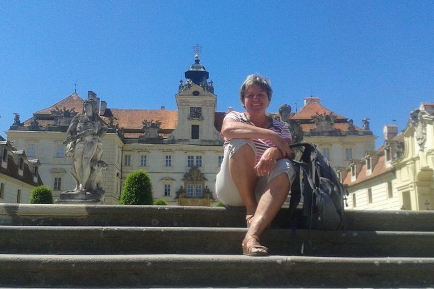 A person sitting on steps with a historic building and statues in the background. 5