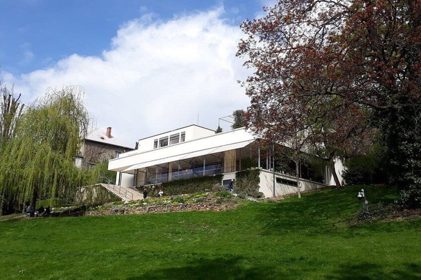 A modern house with a sloped roof, surrounded by a well-maintained lawn and a tree with autumn leaves. 4