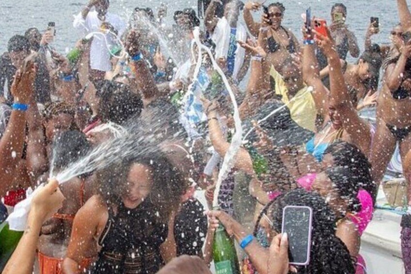 Un grupo de personas en un bote, algunas sosteniendo botellas, con agua salpicando. 4