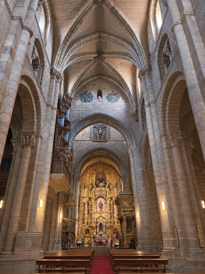 An interior of a cathedral with high vaulted ceilings, arched columns, and an ornate altar. 5