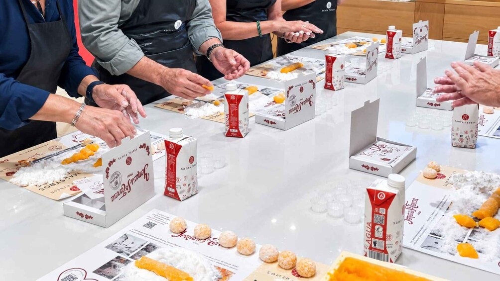 A group of people serving food at a table with Santa Teresa branded products. 4