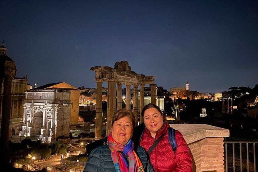 Deux personnes se tiennent devant des ruines antiques, avec des colonnes, la nuit. 3