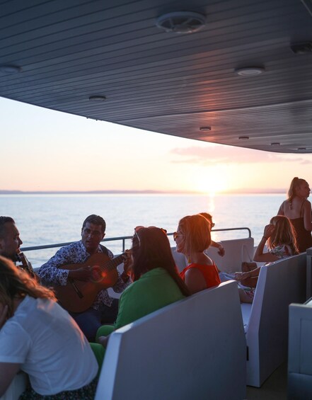 A group of people on a boat with a sunset in the background. 1