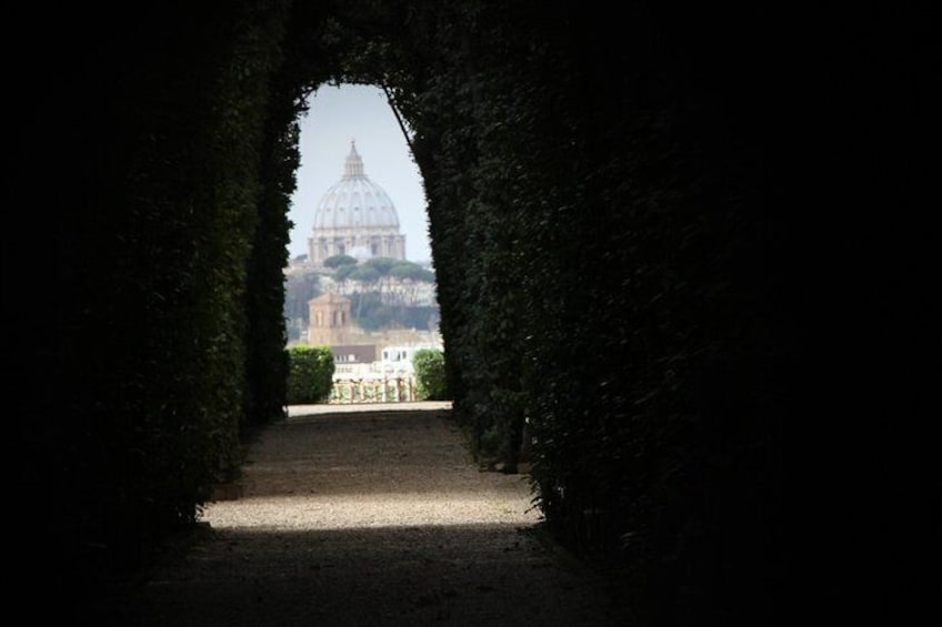 An arched pathway leading to a domed building, surrounded by greenery. 4