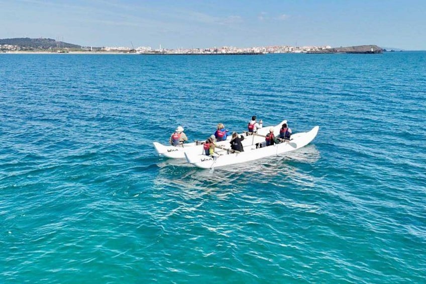 A white boat with several people on a turquoise sea, with a coastal town in the background. 2