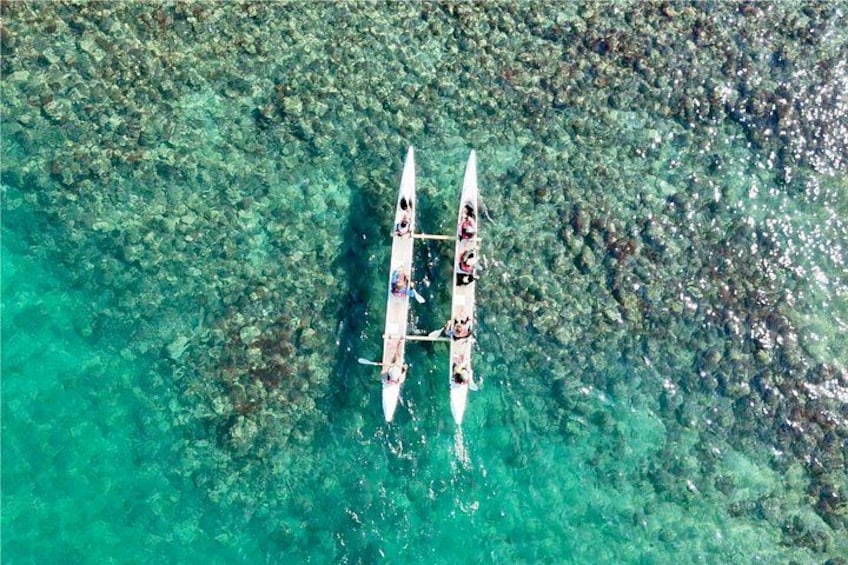 A canoe with two paddlers on a clear turquoise sea. 5