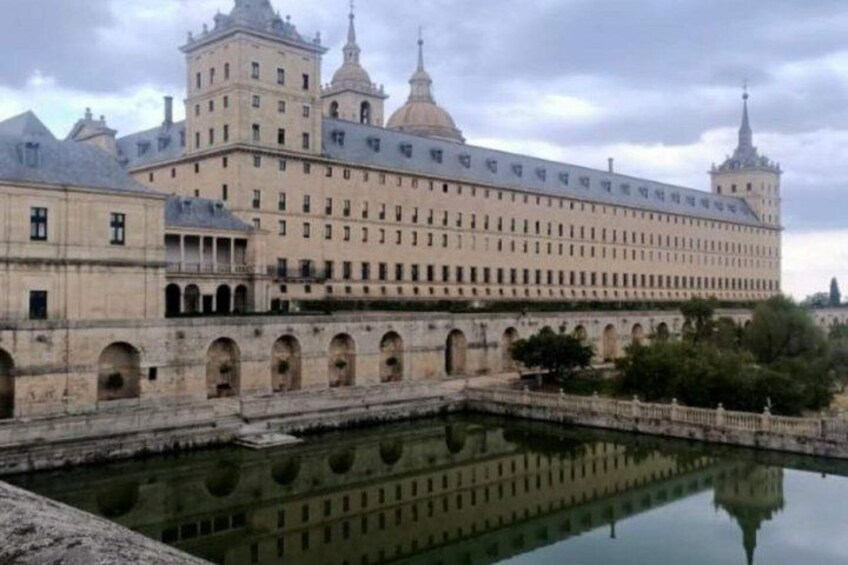 A large historic building with multiple towers and a reflective water body in front. 2