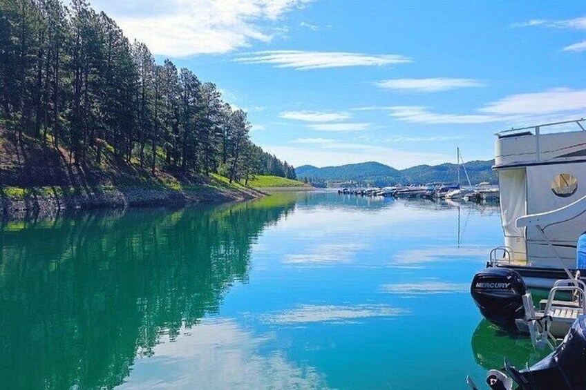 A calm river with boats, a forested bank, and distant hills. 1