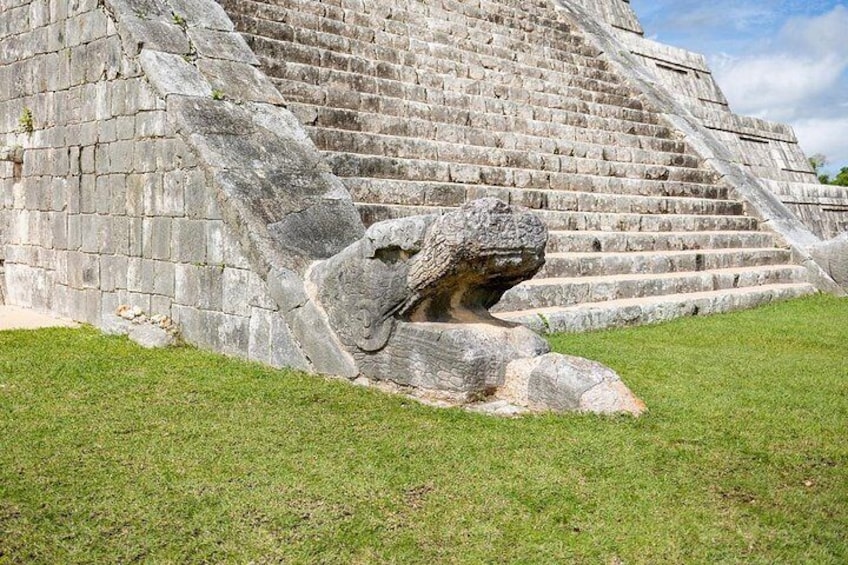 Una escalera de piedra conduce a una estructura piramidal con una gran figura de piedra tallada en la base. 4