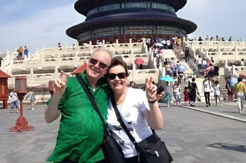 A couple posing in front of a historic building with a circular structure and stairs leading up to it. 2
