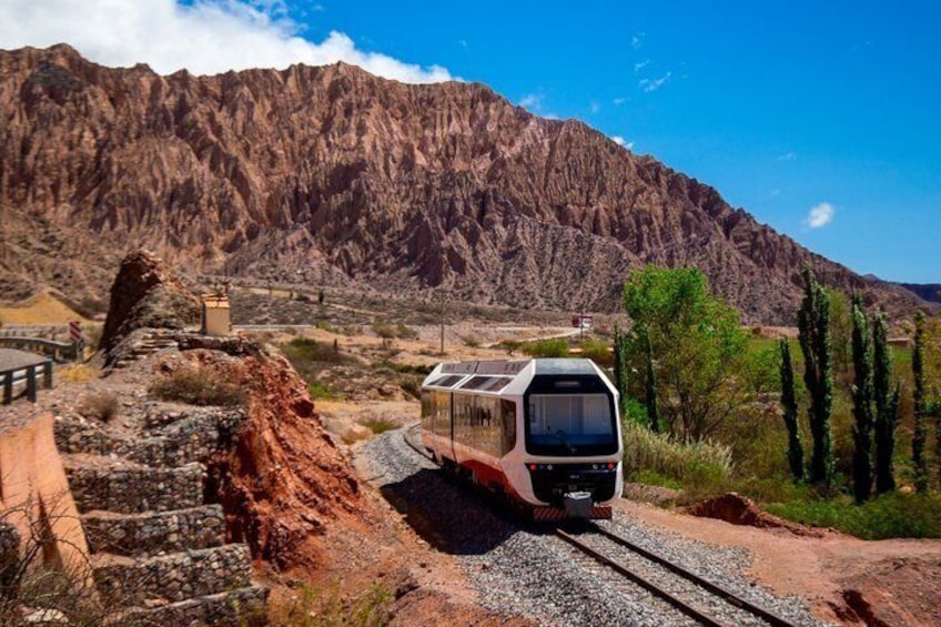 A train on tracks with a mountainous backdrop. 2
