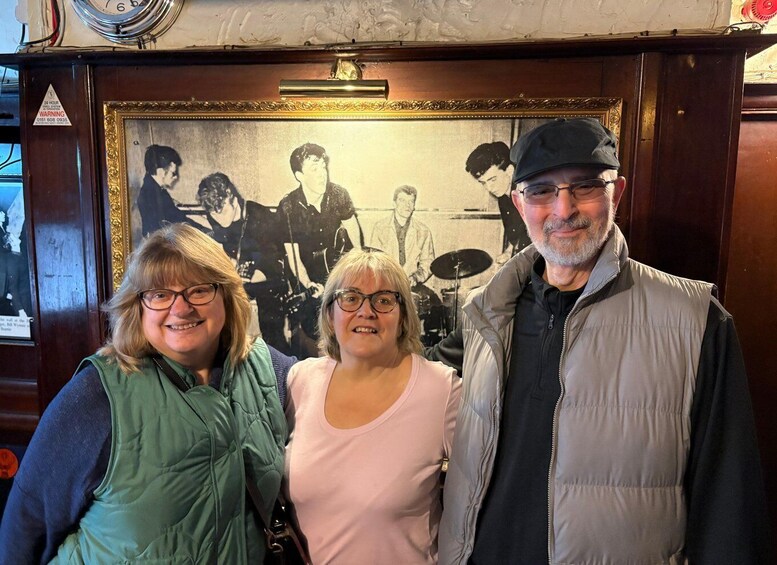 Three people standing in front of a framed black and white photograph. 4