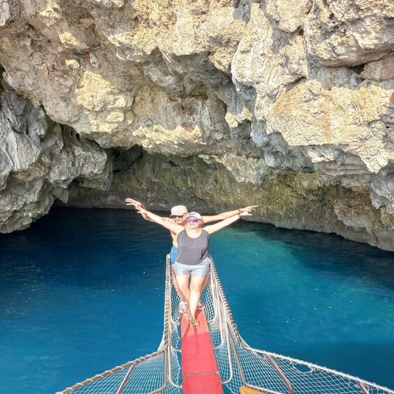 A person standing on a rope bridge over a body of water with rocky cliffs in the background. 3