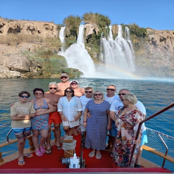 A group of people on a boat near a waterfall with a rainbow. 5