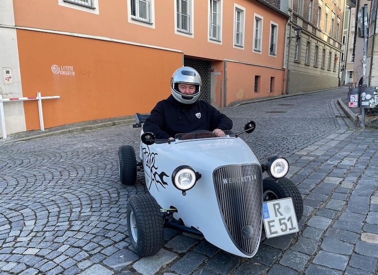 A vintage car with a license plate 'R E 51' parked on a cobblestone street. 5