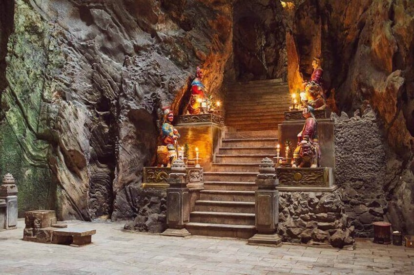 Un templo rupestre con estatuas y escalones que conducen a un altar central. 1