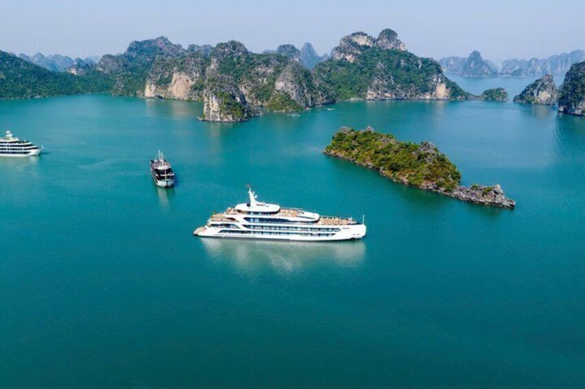 Un navire de croisière dans une baie turquoise, entouré d’îles verdoyantes et de falaises rocheuses. 3