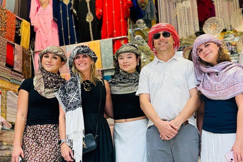 Un grupo de personas en un mercado, con diversos textiles y telas de fondo. 3