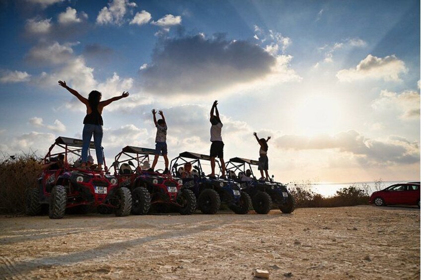 A group of people on all-terrain vehicles (ATVs) with a sunset in the background. 5