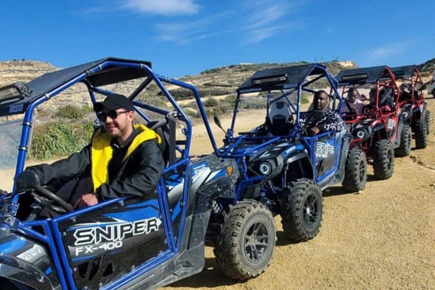 A line of off-road vehicles on a gravel path with a clear sky. 2
