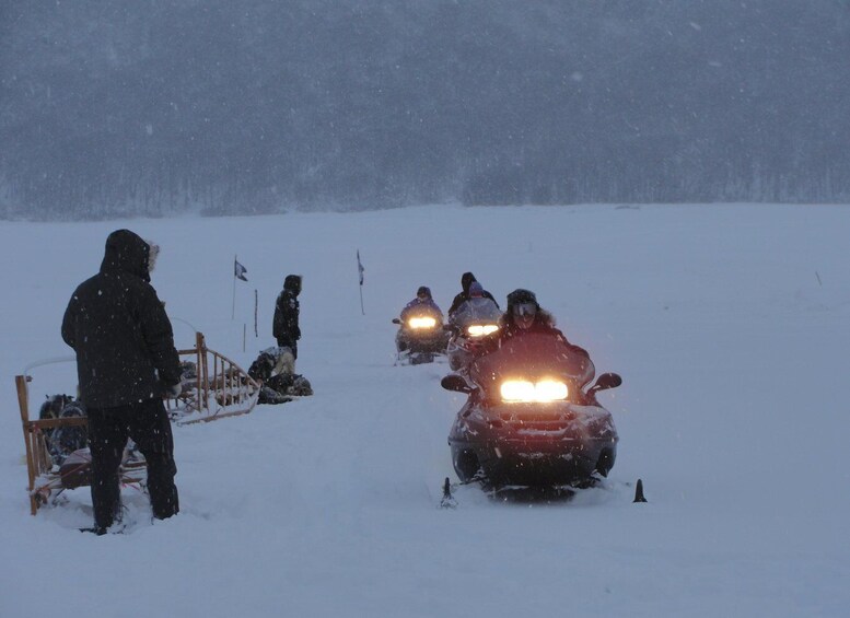 A group of people on snowmobiles in a snowy landscape. 5