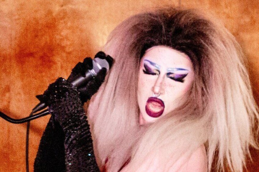 A person with long hair wearing a black outfit and a microphone. 2