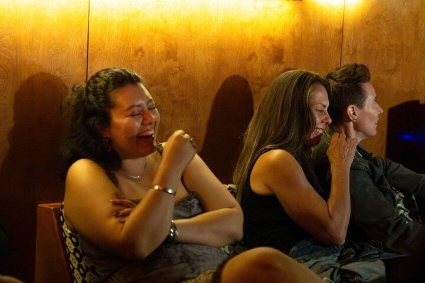 People sitting closely together in a dimly lit room with wooden walls. 3