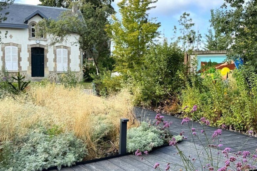 Ett hus med en trädgård, en träveranda och en väggmålning i bakgrunden. 2