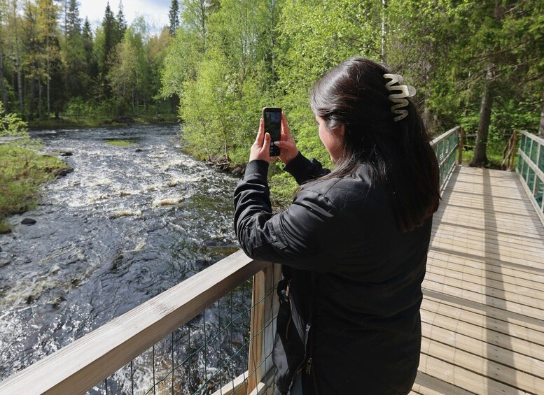 A person taking a photo of a river with a bridge in the background. 5