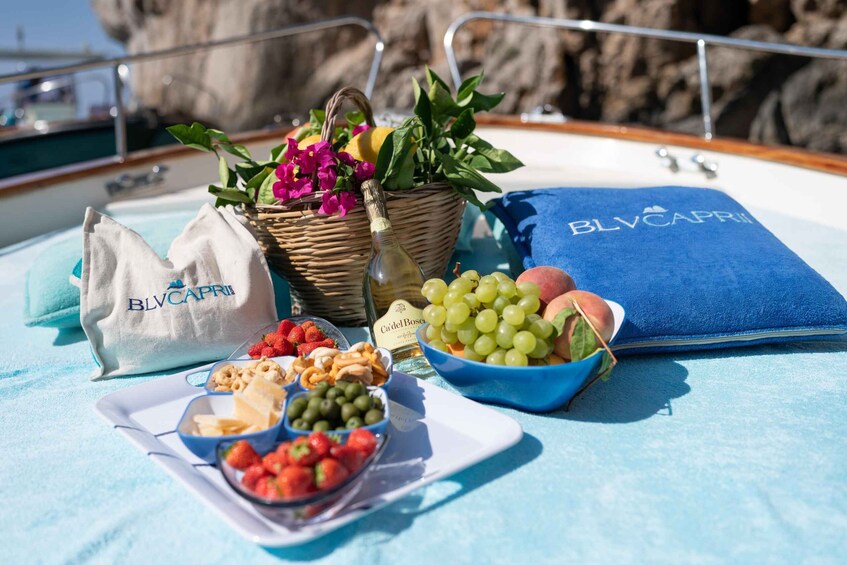 A boat deck with a table set with food, a basket of flowers, and a bottle of wine. 5