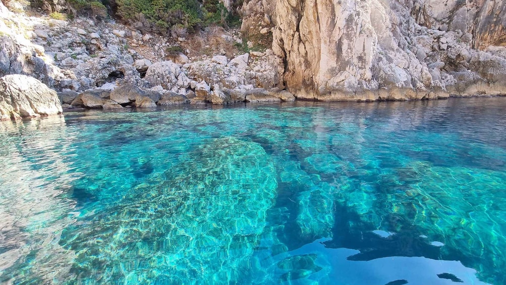 A clear turquoise pool surrounded by rocky cliffs. 2