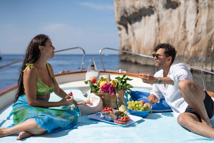 Two people on a boat with a basket of fruits and a table with snacks. 4