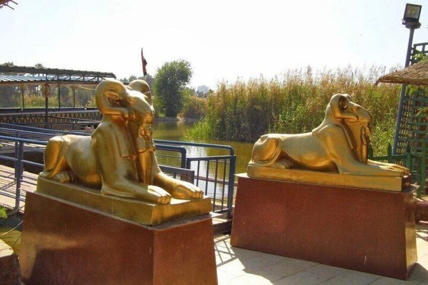 Two golden sphinx statues on pedestals by a river. 3