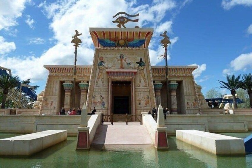 An ancient Egyptian temple with a large entrance, a central obelisk, and a surrounding pool. 1