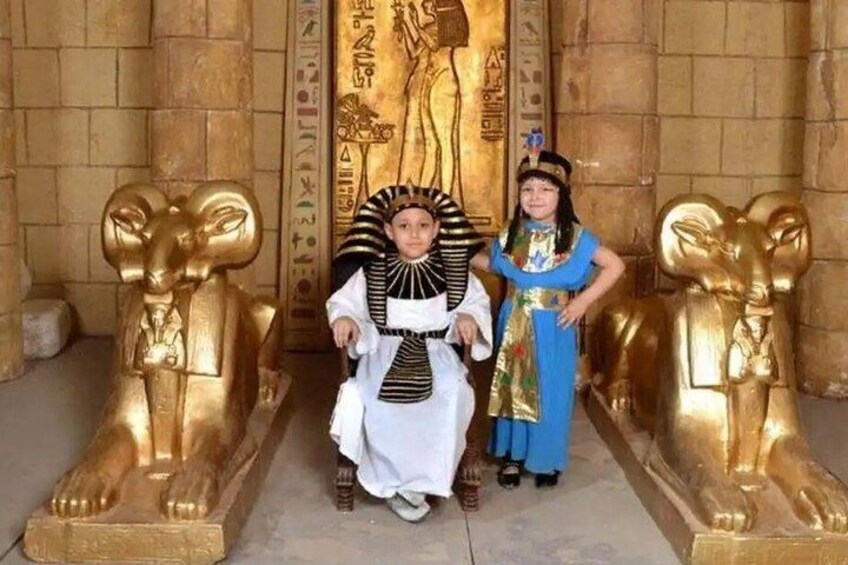 A person in ancient Egyptian attire standing between two golden sphinx statues. 4