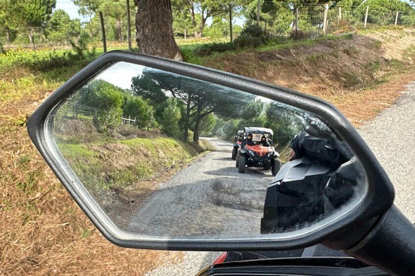 Espejo retrovisor lateral de un vehículo que refleja un camino de tierra con otro vehículo adelante. 3