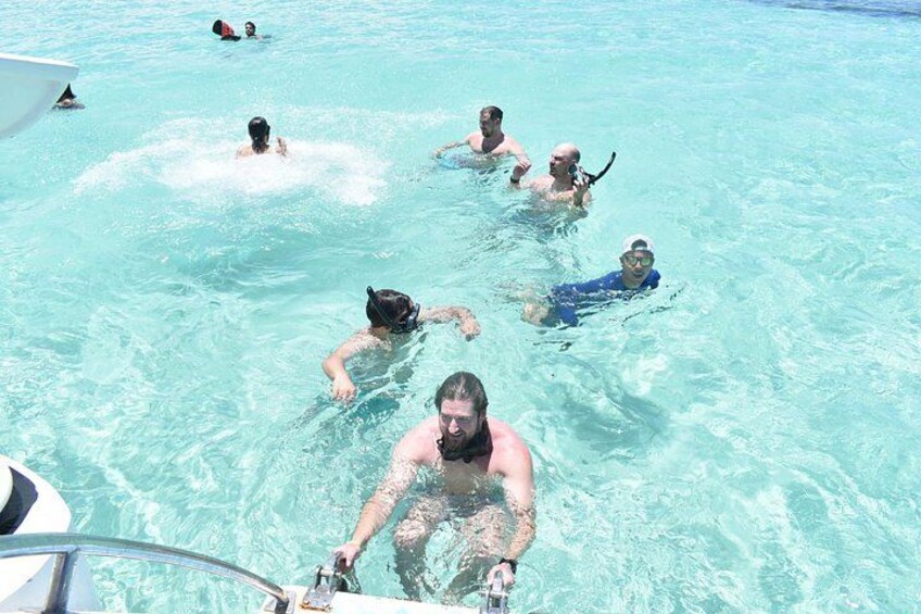 People swimming in a clear blue pool with a boat in the foreground. 5