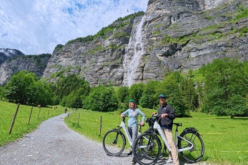 A pathway leading to a waterfall, surrounded by lush greenery and rocky cliffs. 4