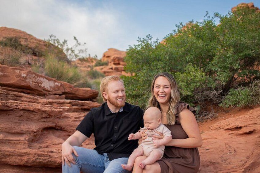 En familie på tre sidder på en klippe med et ørkenlandskab i baggrunden. 2