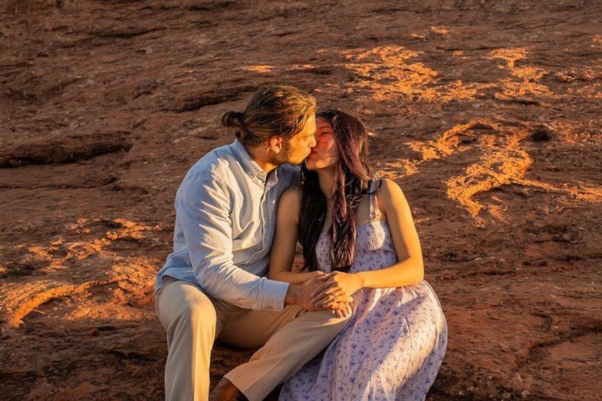 A couple sitting on a rocky surface with a warm glow in the background. 3
