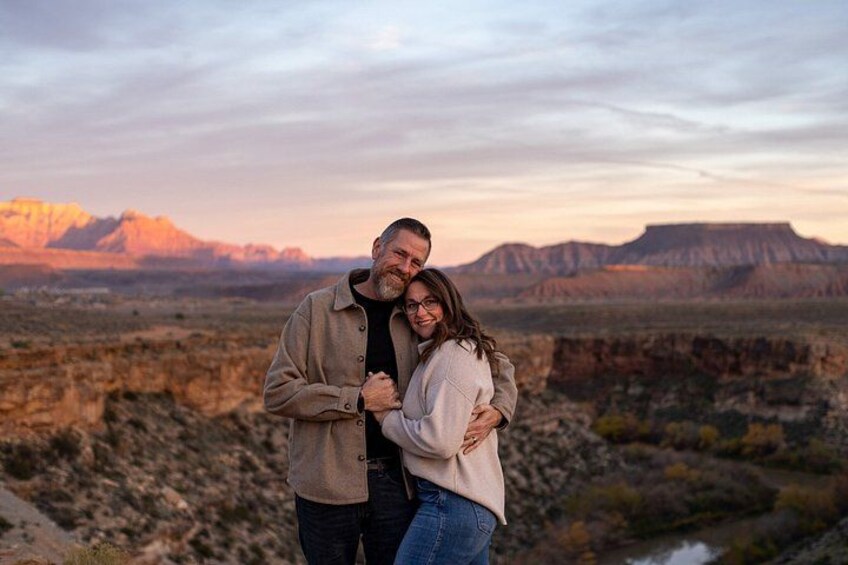 A couple embracing in a desert landscape with mountains in the background. 4
