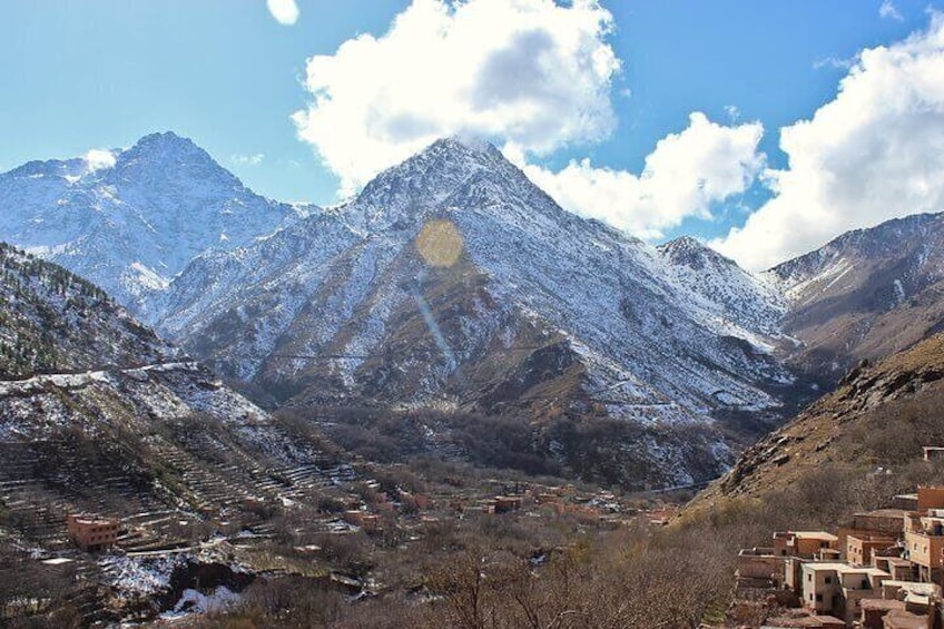 A mountainous landscape with snow-covered peaks, a valley with buildings, and a clear sky. 5