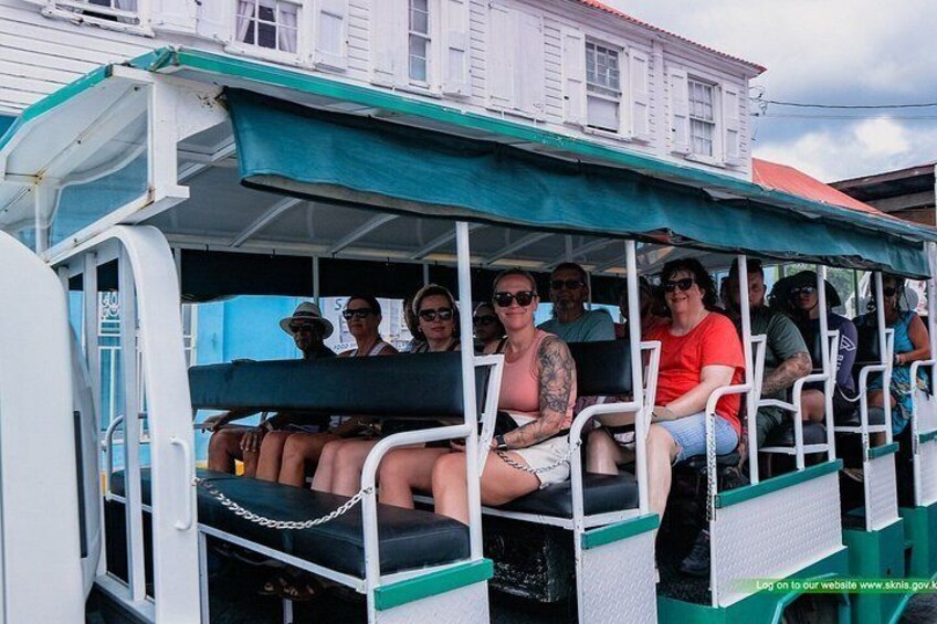 A group of people on a boat with a green canopy, white walls, and a blue railing. 2