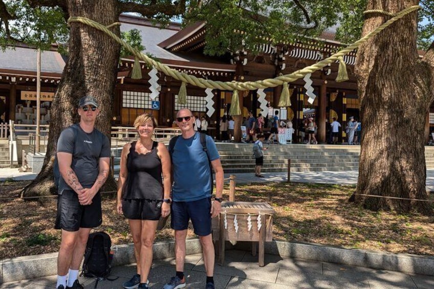 A group of people standing in front of a traditional Japanese building with a wooden structure and a rope bridge. 3