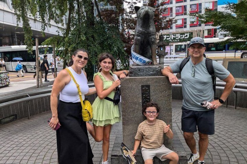 A group of people posing with a statue in an urban setting. 4