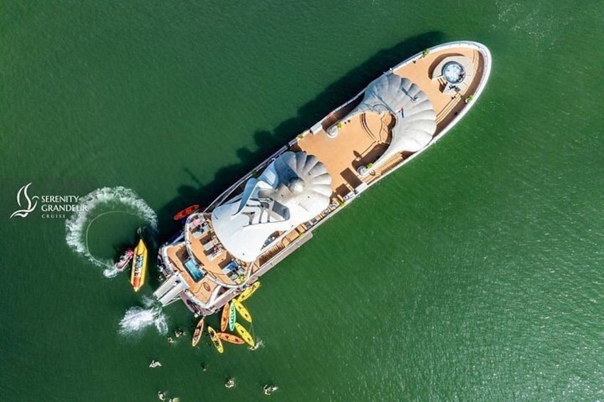 A large cruise ship with multiple decks, a helipad, and several smaller boats around it. 2