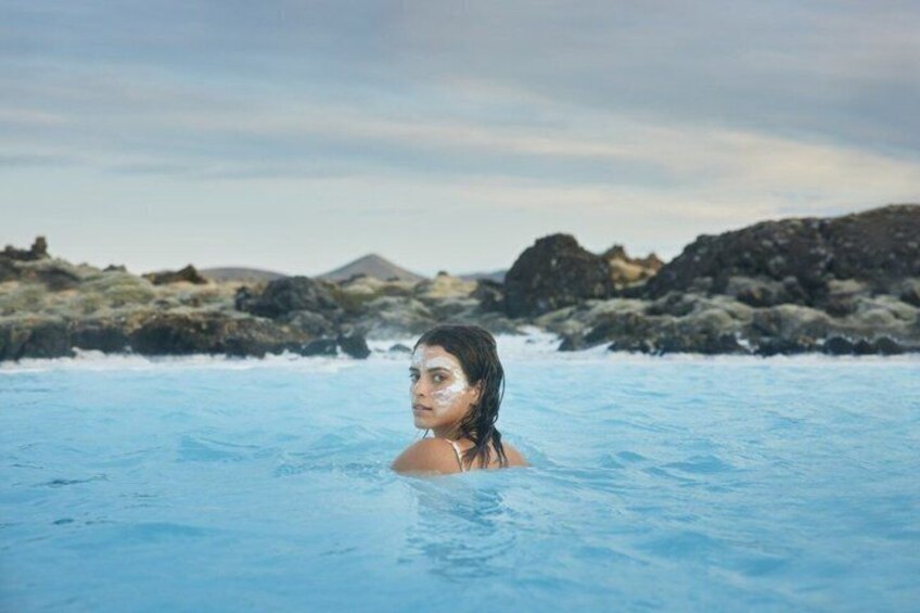 A person in a geothermal pool surrounded by rocky terrain and mountains. 3